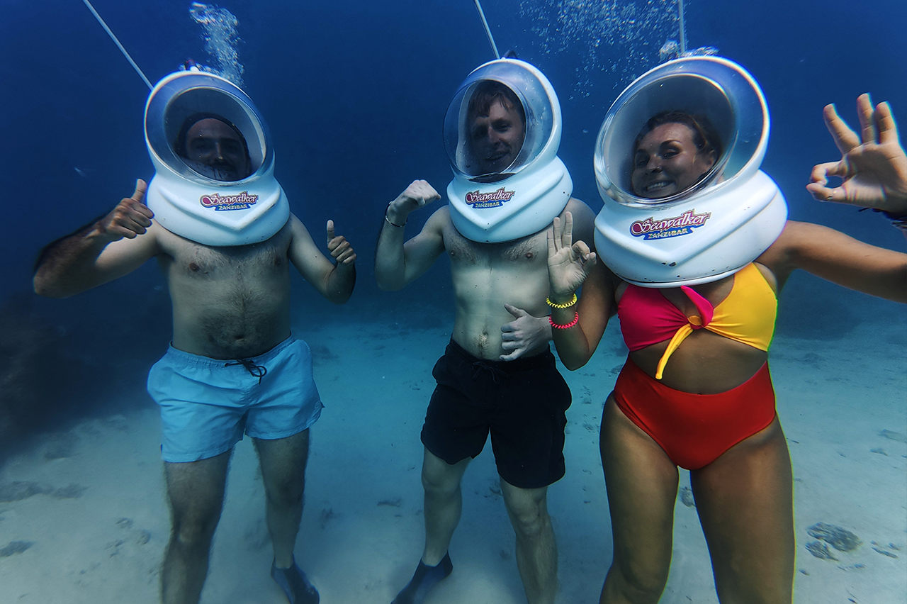 A person enjoying the Zanzibar Seawalk experience underwater surrounded by fish.