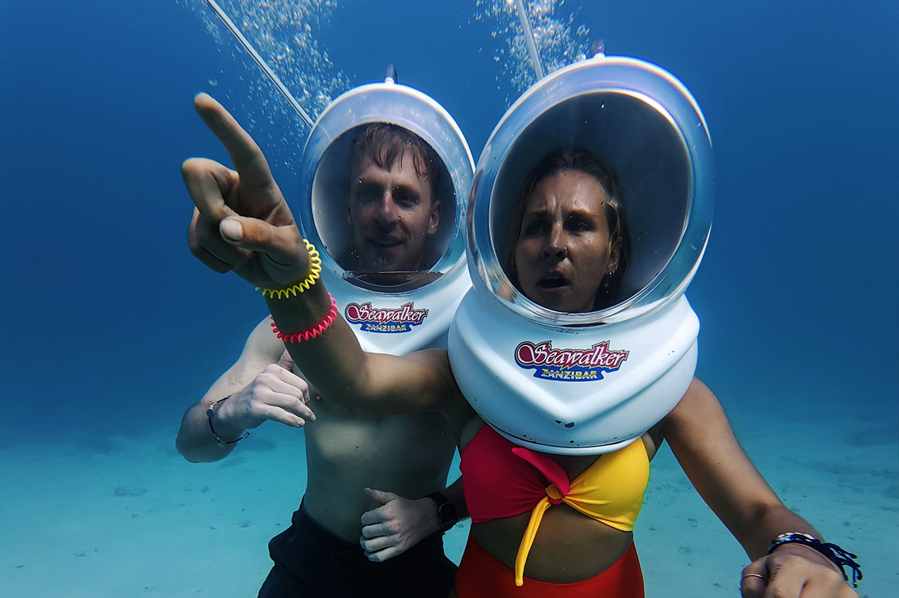 A person enjoying the Zanzibar Seawalk experience underwater surrounded by fish.